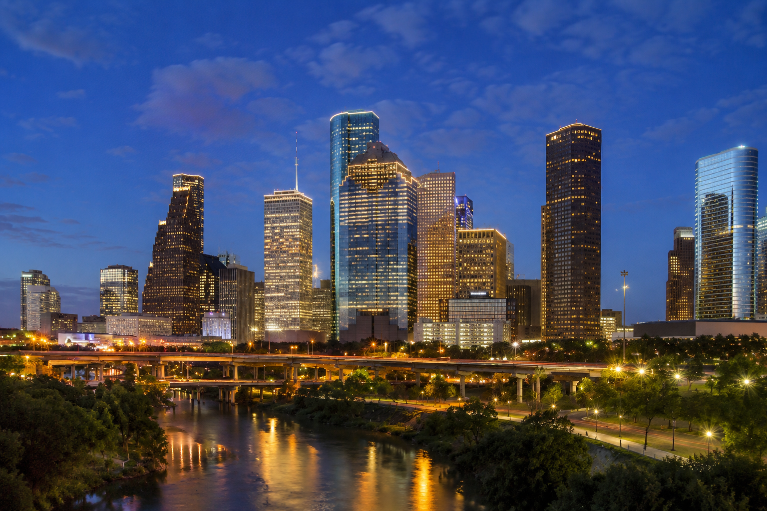 Houston skyline at dusk with illuminated skyscrapers reflecting in the bayou